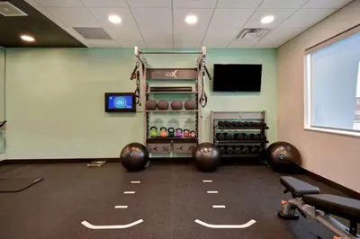a gym with dumbbells and a tv in a room at Tru By Hilton Auburn, In in Auburn