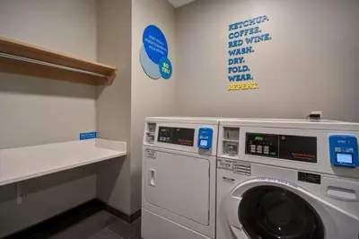 a laundry room with a washing machine and a sign at Tru By Hilton Auburn, In in Auburn
