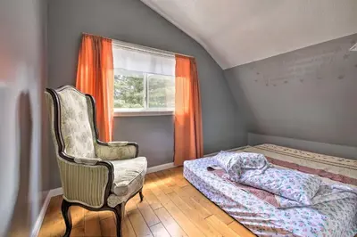 a bedroom with a bed and a chair and a window at Loft Unplugged with Outdoor Space in Amish Country! in Burton