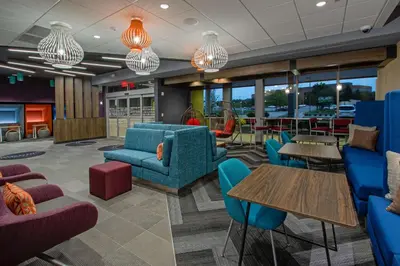 a lobby with blue chairs and tables and windows at Tru By Hilton Columbus Airport in Columbus