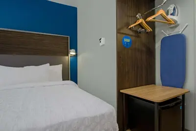 a bedroom with a bed and a table and a blue wall at Tru By Hilton Columbus Airport in Columbus
