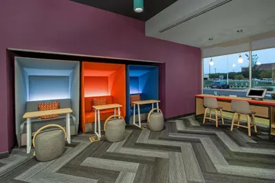 a room with chairs and a table and a purple wall at Tru By Hilton Columbus Airport in Columbus