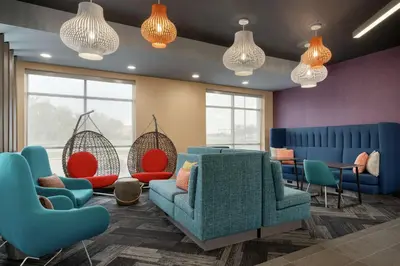 a waiting room with blue and red chairs and windows at Tru By Hilton Sandusky, Oh in Sandusky