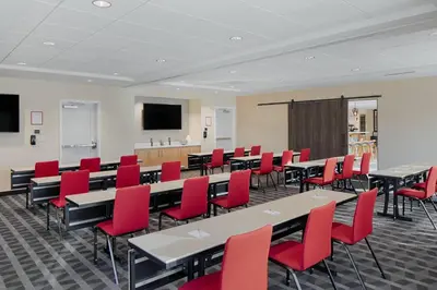 a classroom with tables and red chairs and a screen at TownePlace Suites Columbus Hilliard in Hilliard