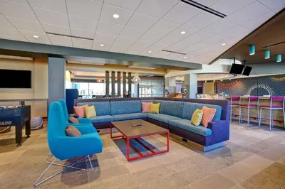 a lobby with a blue couch and chairs and a table at Tru By Hilton Monroe, Oh in Monroe