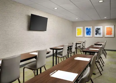a conference room with tables and chairs and a tv on the wall at Home2 Suites Troy, OH in Troy