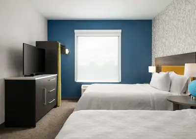a hotel room with two beds and a flat screen tv at Home2 Suites Troy, OH in Troy