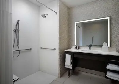 a bathroom with a sink and a shower with a mirror at Home2 Suites Troy, OH in Troy