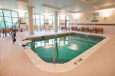 a swimming pool in a building with tables and chairs at Courtyard by Marriott Cincinnati Midtown/Rookwood in Cincinnati
