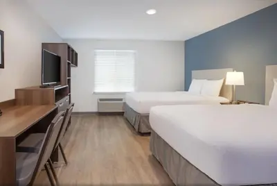 a hotel room with two beds and a desk at WoodSpring Suites Columbus Urbancrest in Grove City