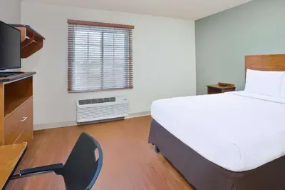 a bedroom with a bed and a desk and a television at WoodSpring Suites Columbus Urbancrest in Grove City