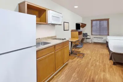 a kitchen with a sink and a refrigerator and a bed at WoodSpring Suites Columbus Urbancrest in Grove City