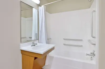 a white bathroom with a sink and a shower at WoodSpring Suites Columbus Urbancrest in Grove City