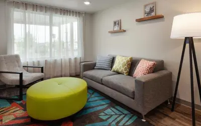 a living room with a couch and a stool and a chair at WoodSpring Suites Columbus Urbancrest in Grove City