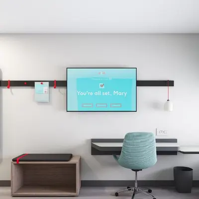 a room with a computer screen on a wall with a chair at Avid Hotels - Cincinnati N - West Chester by IHG in West Chester