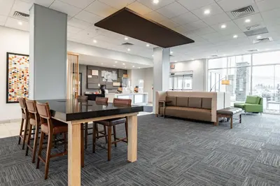 a room with a table and chairs and a couch at Holiday Inn Express & Suites - Moundsville by IHG in Moundsville