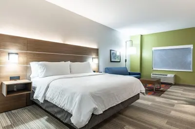 a hotel room with a large bed and a chair at Holiday Inn Express & Suites - Moundsville by IHG in Moundsville