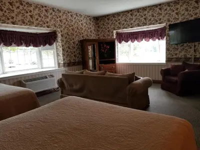 a hotel room with two beds and a couch and windows at Inn at Amish Door in Wilmot