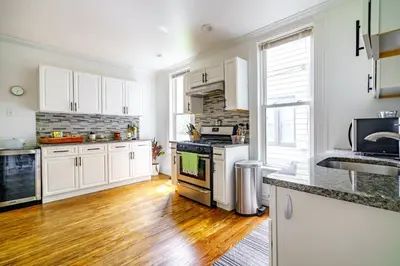 a kitchen with white cabinets and a wooden floor at Jungle House Luxury Stays - Columbus Downtown Short North in Columbus