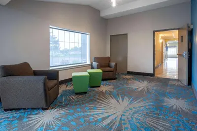 a waiting room with couches and chairs on a carpet at Days Inn by Wyndham Sandusky Cedar Point in Sandusky