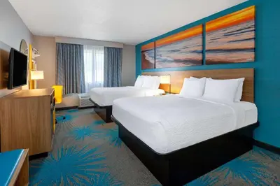 a hotel room with two beds and a flat screen tv at Days Inn by Wyndham Sandusky Cedar Point in Sandusky
