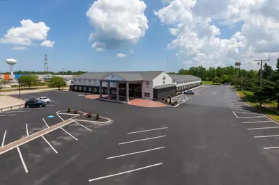 an empty parking lot with a building and a car at Days Inn by Wyndham Sandusky Cedar Point in Sandusky