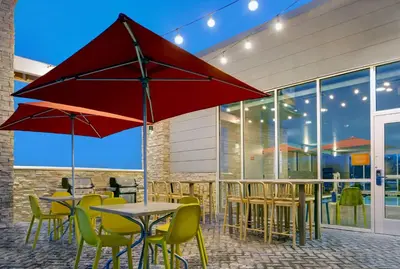 a patio with tables and chairs and a red umbrella at Home2 Suites By Hilton Richmond in Richmond
