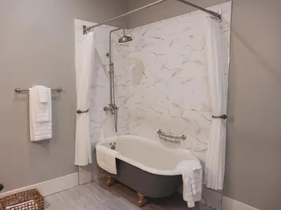 a bath tub in a bathroom with a marble wall at Lee House Inn in Maysville