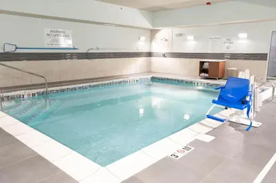 a swimming pool with a blue chair in a room at Holiday Inn Express & Suites Dayton East - Beavercreek by IHG in Beavercreek