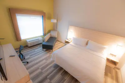a bedroom with a bed and a chair and a window at Holiday Inn Express & Suites Dayton East - Beavercreek by IHG in Beavercreek