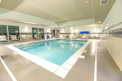 a large swimming pool in a building with tables and chairs at Holiday Inn Express & Suites Dayton East - Beavercreek by IHG in Beavercreek