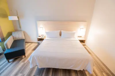 a bedroom with a large white bed and a chair at Holiday Inn Express & Suites Dayton East - Beavercreek by IHG in Beavercreek