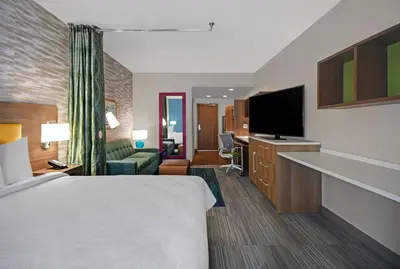a hotel room with a bed and a flat screen tv at Home2 Suites By Hilton Springdale Cincinnati in Springdale