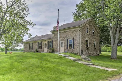 an old brick house with an american flag on it at Historic Ottawa Lake House Deck, Barn and 96 Acres! in Sylvania