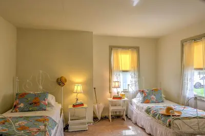 a bedroom with two beds and a table and two windows at Historic Ottawa Lake House Deck, Barn and 96 Acres! in Sylvania