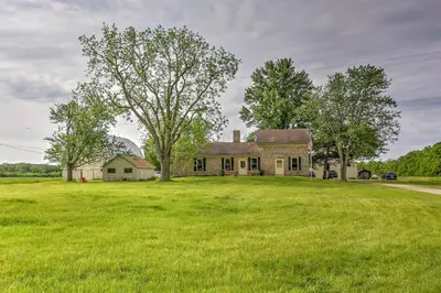an old house with a large field of grass at Historic Ottawa Lake House Deck, Barn and 96 Acres! in Sylvania