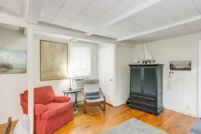 a living room with a red couch and a chair at Walk to Lake Historic Lakeside Marblehead Cottage in Lakeside
