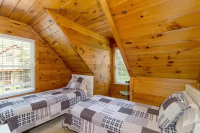 two beds in a log cabin bedroom with wooden walls at Scotch Pine . Trailside Lodging in Millersburg