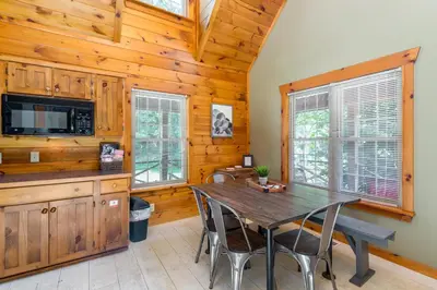 a dining room with a wooden table and chairs at Scotch Pine . Trailside Lodging in Millersburg