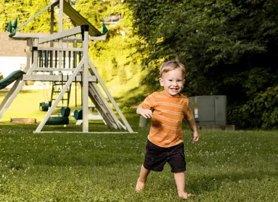 a young boy is standing in the grass at Scotch Pine . Trailside Lodging in Millersburg