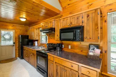 a kitchen with wooden cabinets and a stove and microwave at Scotch Pine . Trailside Lodging in Millersburg