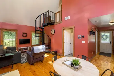 a living room with a spiral staircase and a table at White Pine . Trailside Lodging in Millersburg