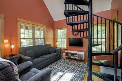 a living room with a couch and a staircase at White Pine . Trailside Lodging in Millersburg