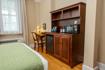 a room with a bed and a cabinet with a microwave at Mills Park Hotel in Fairborn