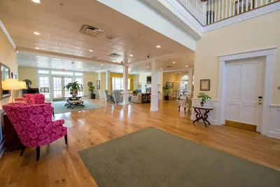 a large living room with pink chairs and a rug at Mills Park Hotel in Fairborn