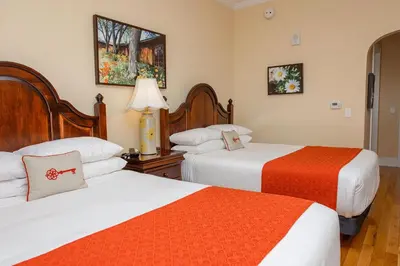 a hotel room with two beds with orange and white sheets at Mills Park Hotel in Fairborn