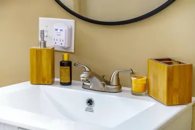 a bathroom sink with a mirror and some soap and cosmetics at Jungle House Luxury Stays - Columbus Downtown Short North in Columbus