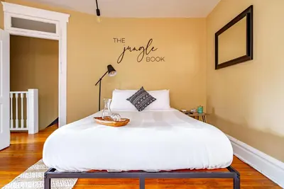 a bedroom with a white bed with a sign on the wall at Jungle House Luxury Stays - Columbus Downtown Short North in Columbus