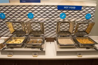 a counter with trays of food on display in a store at Holiday Inn Express & Suites Dayton North - Vandalia by IHG in Dayton