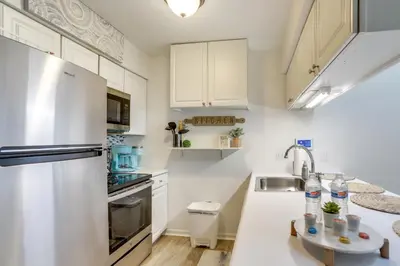 a kitchen with white cabinets and a stainless steel refrigerator at Charming Condo on Lake Erie with Community Pool in Sand Beach